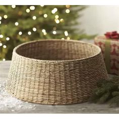 a wicker basket sitting on top of a table next to a christmas tree with lights in the background