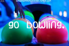 two bowling balls with the words go bowling in white letters on them, and an image of someone reaching for one