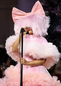 lady in pink and white outfit on stage with microphone