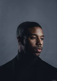 a man with ear buds on his ears looking off to the side in front of a gray background