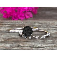 a black diamond ring on top of a wooden table with pink flowers in the background