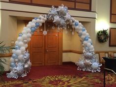 an arch made out of balloons and snowflakes is in the middle of a room