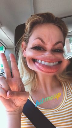 a woman is making the peace sign with her hand and wearing a yellow striped shirt