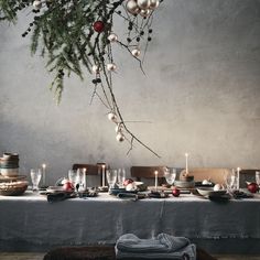 the table is set for christmas dinner with silverware and ornaments hanging from the branches