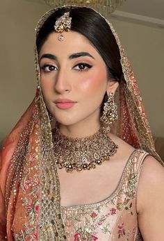 a woman wearing a bridal outfit with jewelry on her head and veil over her face