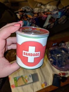 a person holding a cup with the word bandage on it in front of a pile of other items