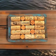 several wine corks are arranged on a wooden table next to the water in front of a boat