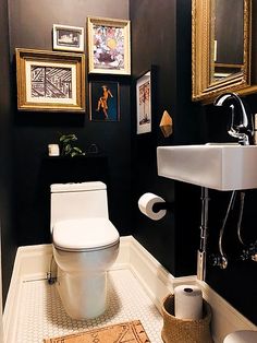 a white toilet sitting in a bathroom next to a sink and pictures on the wall