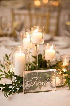 candles are placed on the table with greenery