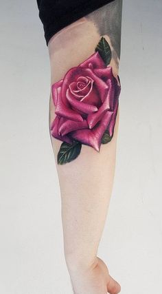 a woman's leg with a pink rose tattoo on her left calf and the bottom part of her arm