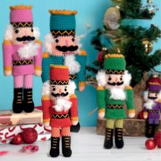 three crocheted nutcrackers standing next to a christmas tree