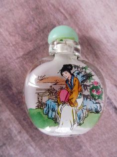 a small glass bottle with an image of a woman on it