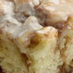 a piece of cinnamon roll with icing sitting on top of a white plate next to a fork