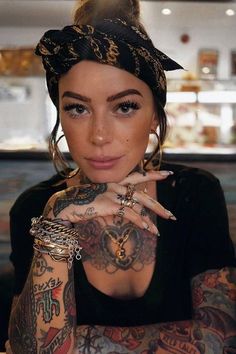 a woman with many tattoos on her arms and hands is posing for the camera while wearing a bandana