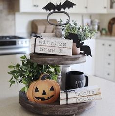 a three tiered tray with pumpkins, books and witches brew sign on it