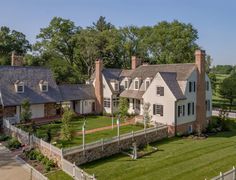 an aerial view of a large home with lots of grass and trees in the background