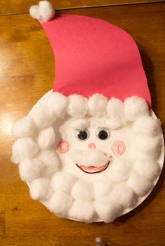 a paper plate with a santa hat on top of it, sitting on a wooden table