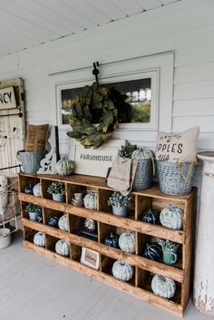 a shelf filled with potted plants on top of a wooden floor next to a white wall