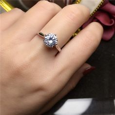 a woman's hand holding a ring with a diamond in the middle and on top of it