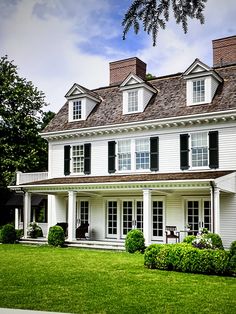 a large white house sitting on top of a lush green field