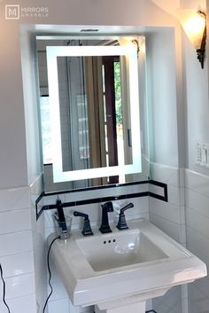 a white sink sitting under a bathroom mirror next to a wall mounted faucet