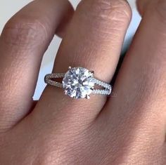 a woman's hand with a diamond ring on top of her finger and the engagement band