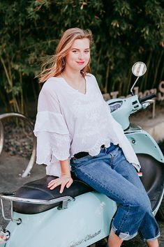 a woman sitting on top of a blue scooter