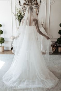 a woman wearing a wedding veil in front of a chandelier