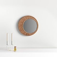 a round mirror on the wall next to two candles and a candle holder in front of it