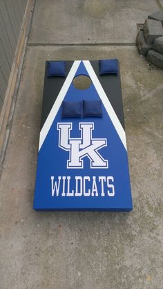 a blue and white cornhole game sitting on the side of a street next to a building