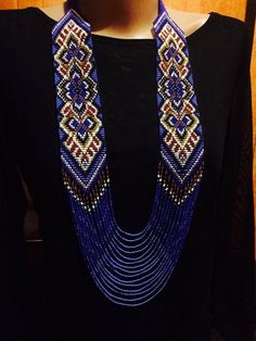 a woman wearing a blue beaded necklace and black shirt with red, white, and blue beads on it