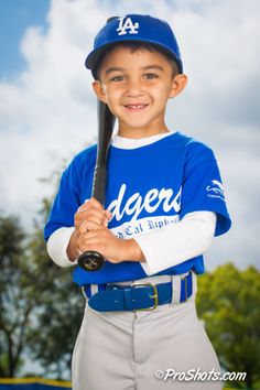 a young boy holding a baseball bat on top of a field