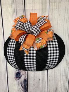 a black and white pumpkin with an orange bow on it's head sitting on a wooden surface