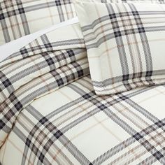 the comforter is made up with plaid sheets and pillow shampoos on it