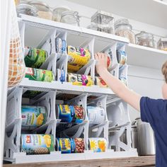 a young boy reaching for canned food in a pantry