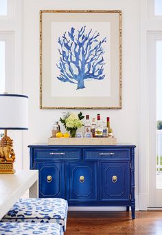 a blue buffet table with drinks on it and a painting hanging above the top shelf