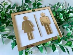 an image of a bathroom sign with leaves in the background