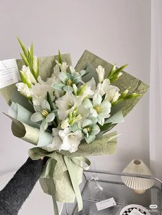 a bouquet of white flowers sitting on top of a glass table next to a card