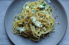 a plate full of pasta with cheese and parmesan on the top, sitting on a table cloth