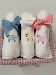 three baby blankets with sheep on them are in a small basket, one is pink and the other is blue