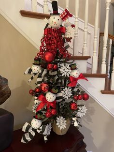 a decorated christmas tree with snowmen and ornaments on it in front of the banister