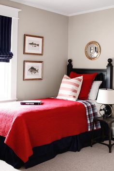 a red and blue bed in a bedroom with pictures on the wall next to it