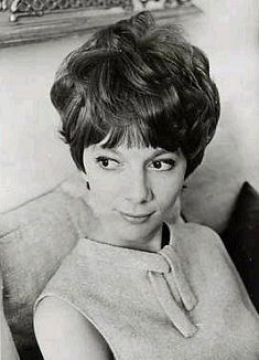 an old black and white photo of a woman with short hair sitting in a chair