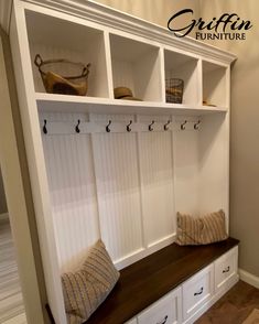 a white bench with some baskets on top of it next to a wall mounted coat rack