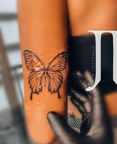 a woman's arm with a butterfly tattoo on it