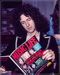 a man with long curly hair holding up a music life magazine in his right hand