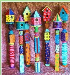 several colorful birdhouses are lined up against a pink background