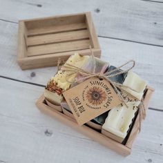 a wooden box filled with soaps on top of a white wood floor next to a brown tag