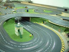 a model train track set with cars and trucks on the tracks in an indoor setting