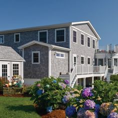 a house with flowers in the front yard and stairs leading up to the second story